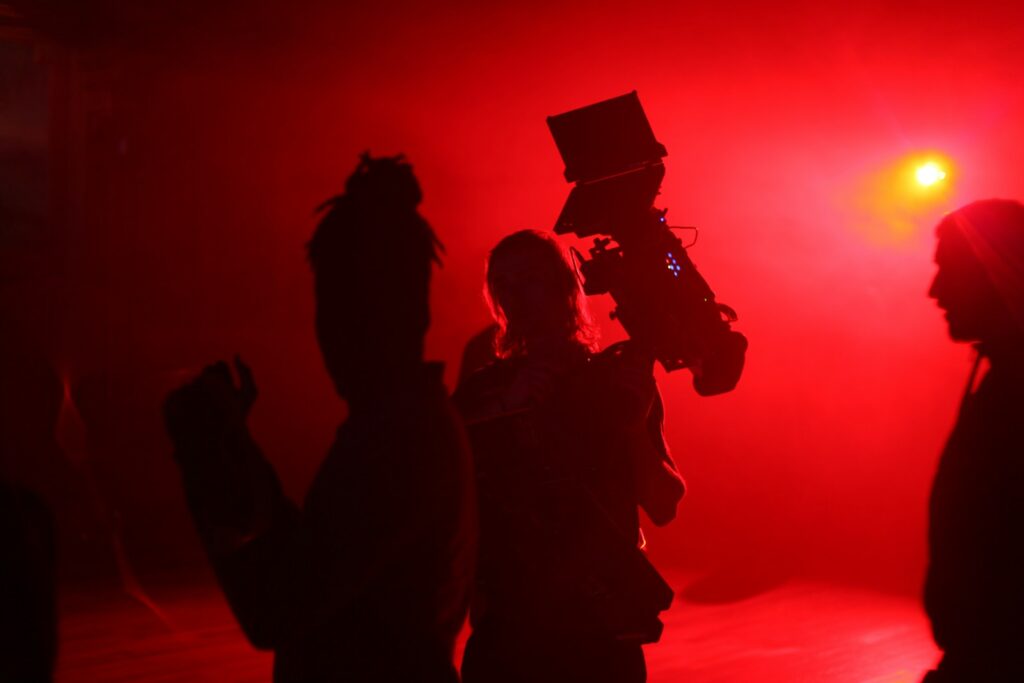 Film crew working under red production lights at night